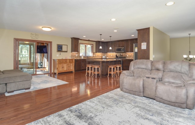 living area with dark wood-style floors, recessed lighting, and a notable chandelier