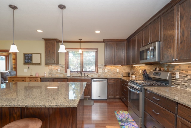 kitchen with light stone counters, dark wood-style floors, decorative light fixtures, decorative backsplash, and appliances with stainless steel finishes