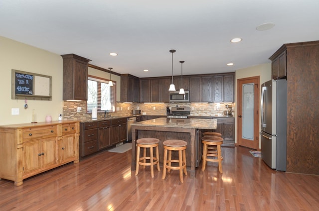 kitchen with a kitchen island, appliances with stainless steel finishes, dark wood finished floors, and dark brown cabinets