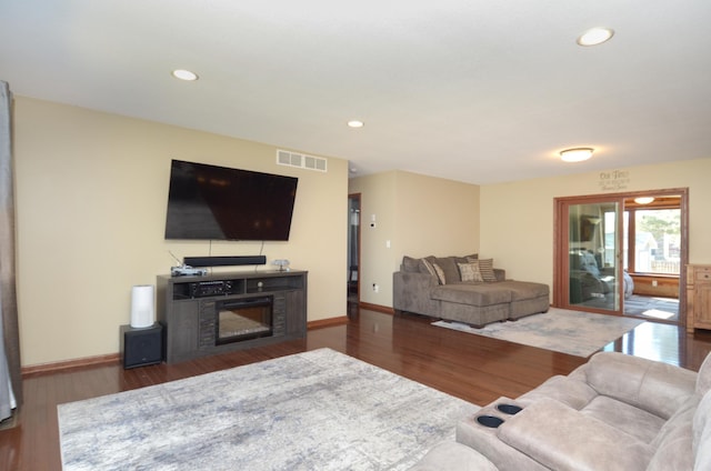 living room with baseboards, visible vents, a glass covered fireplace, wood finished floors, and recessed lighting