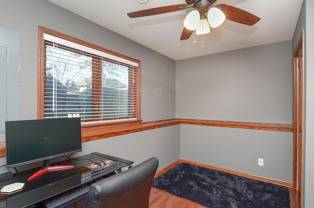 office area with a ceiling fan, baseboards, and wood finished floors