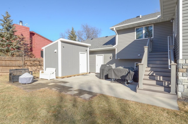 rear view of property with an outbuilding, a patio, stairway, a storage shed, and fence