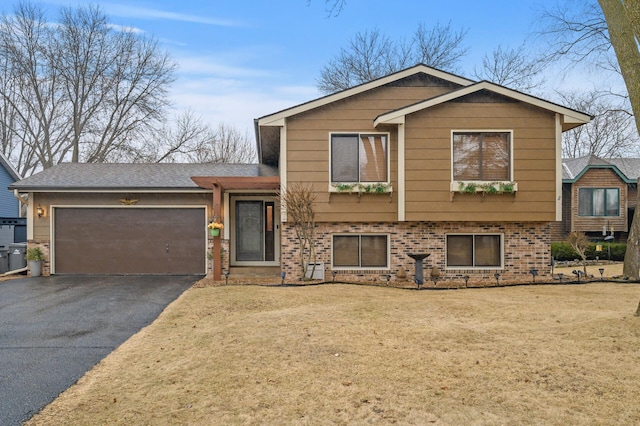 tri-level home featuring aphalt driveway, a front lawn, brick siding, and a garage