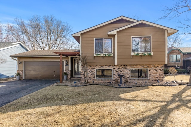 split level home with brick siding, driveway, and a garage