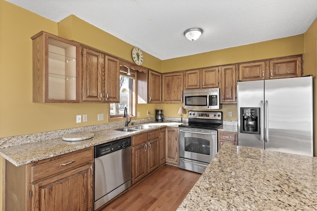 kitchen featuring a sink, brown cabinets, light wood finished floors, and stainless steel appliances