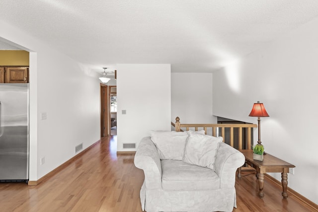 living area with light wood-style flooring, baseboards, and visible vents