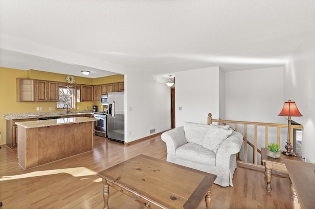 living area with light wood finished floors, visible vents, and baseboards