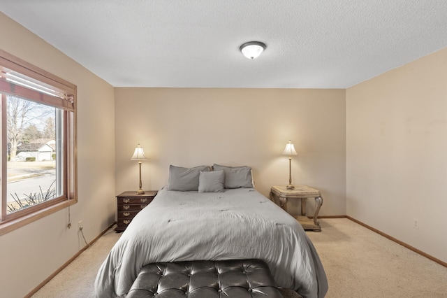 bedroom with light colored carpet, a textured ceiling, and baseboards