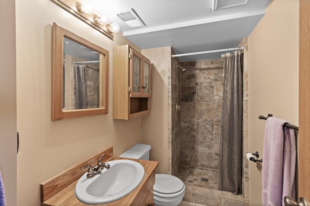 full bathroom featuring a tile shower, visible vents, toilet, and vanity