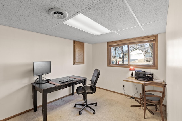 office space featuring a paneled ceiling, baseboards, and light colored carpet