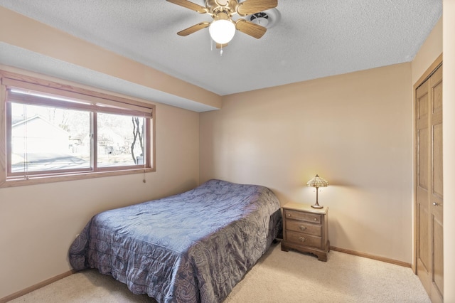 carpeted bedroom with a textured ceiling, baseboards, and a ceiling fan