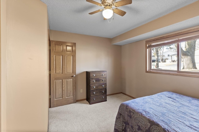 bedroom with light carpet, a textured ceiling, baseboards, and a ceiling fan