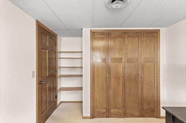 interior space featuring a paneled ceiling, baseboards, and carpet