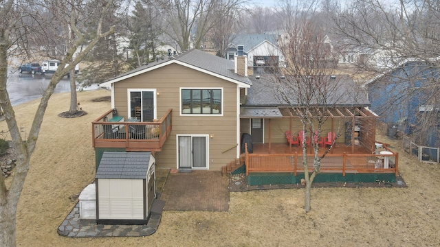 back of property featuring an outbuilding, a lawn, a deck, a shed, and a chimney