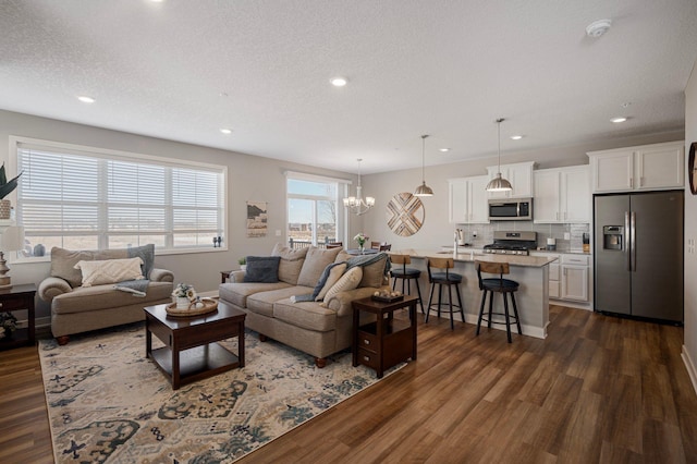 living area with a textured ceiling, a chandelier, dark wood-style flooring, and recessed lighting