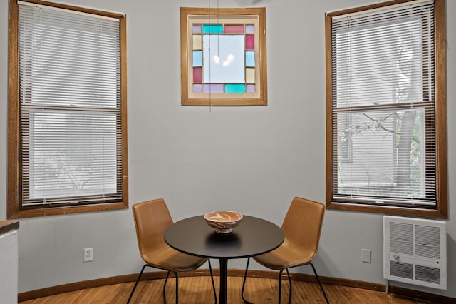 dining area with heating unit, baseboards, and wood finished floors