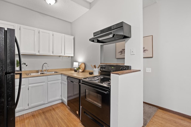 kitchen with under cabinet range hood, a sink, light wood-style floors, white cabinets, and black appliances