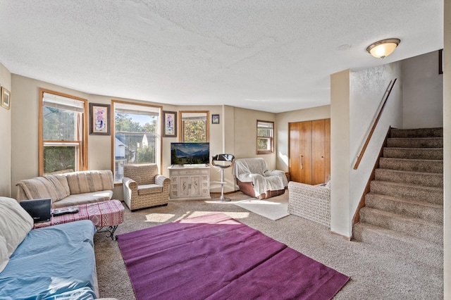 living room with a textured ceiling, stairway, and carpet flooring