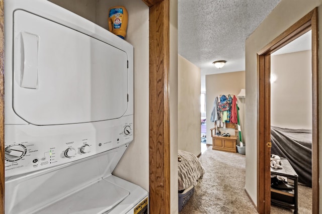 clothes washing area featuring a textured ceiling, laundry area, stacked washing maching and dryer, and carpet flooring