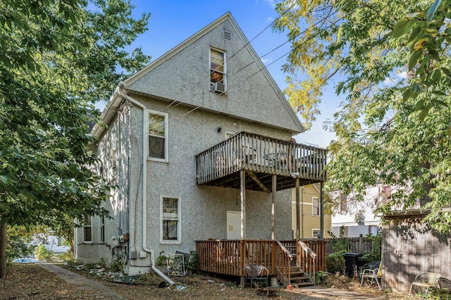 rear view of property featuring a deck, cooling unit, and stucco siding