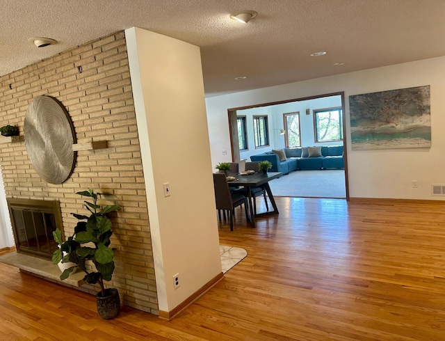 corridor featuring baseboards, visible vents, a textured ceiling, and wood finished floors