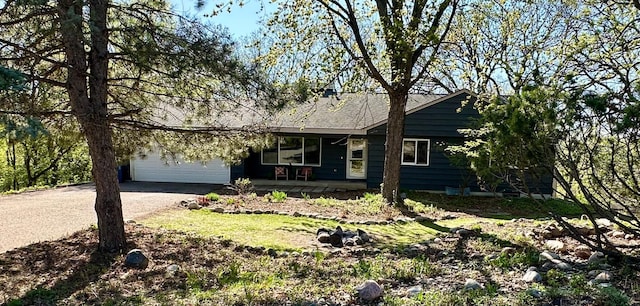 ranch-style home featuring driveway, covered porch, and an attached garage
