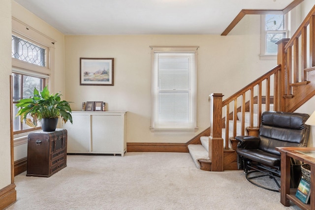 living area featuring carpet, stairway, and baseboards