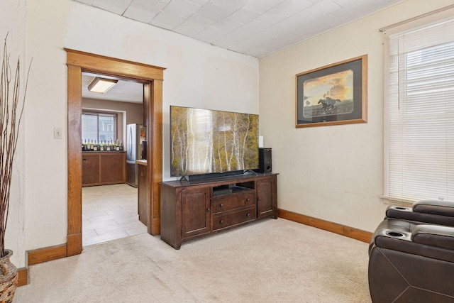 living area featuring light carpet and baseboards