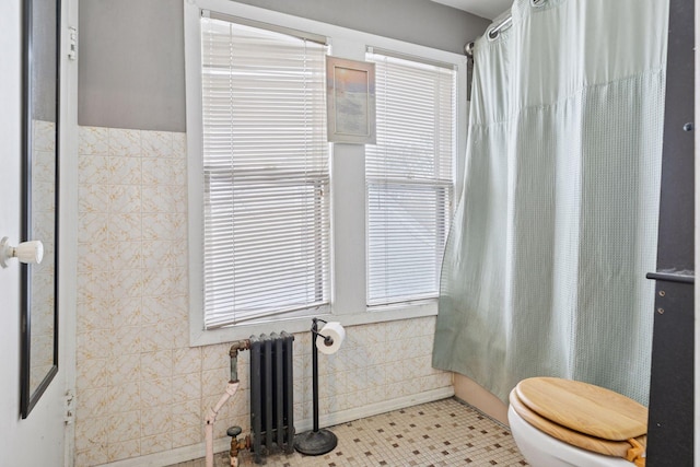 full bathroom with curtained shower, toilet, tile walls, and radiator heating unit