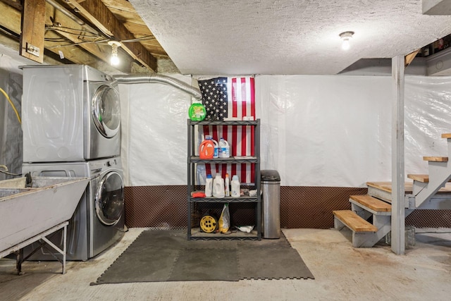 clothes washing area with a sink, laundry area, a textured ceiling, and stacked washer / dryer