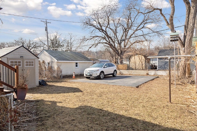 view of yard featuring driveway, an outdoor structure, a storage unit, and fence