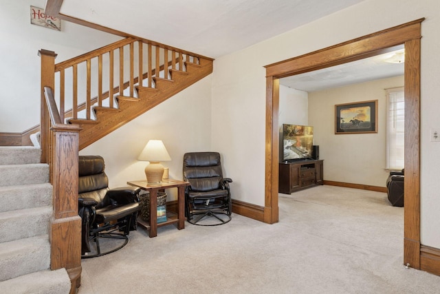 living area featuring carpet flooring, baseboards, and stairs