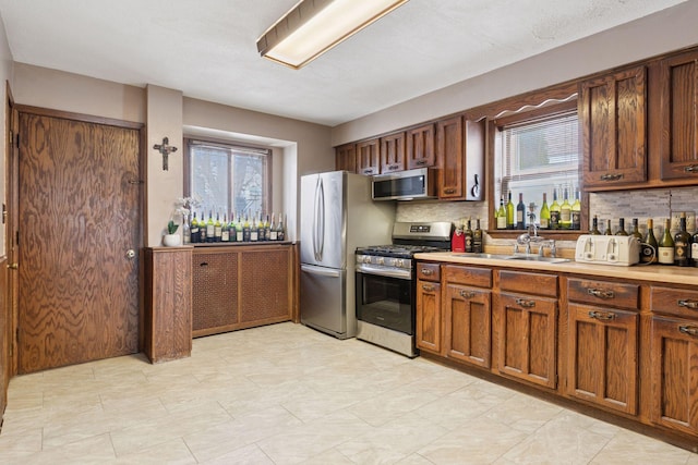 kitchen with appliances with stainless steel finishes, a wealth of natural light, and tasteful backsplash