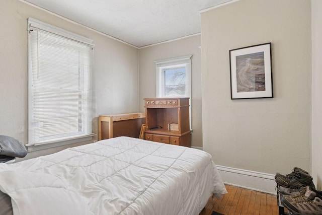 bedroom with baseboards, ornamental molding, and wood-type flooring
