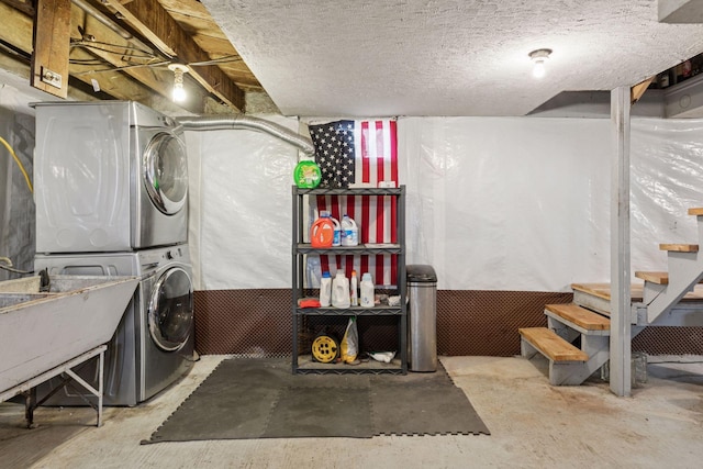 unfinished below grade area with stairs, a textured ceiling, and stacked washer / dryer