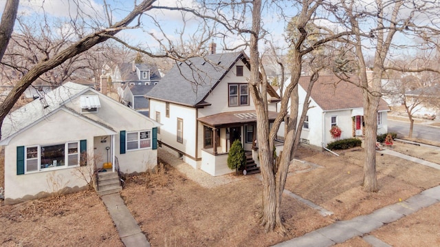 bungalow featuring a chimney, roof with shingles, stucco siding, and a residential view