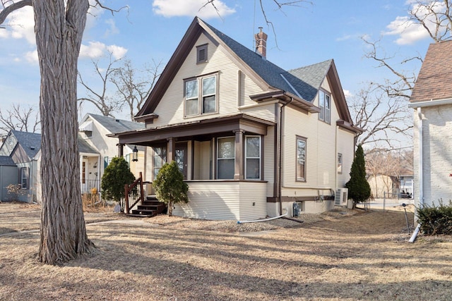view of front of house with roof with shingles, covered porch, and a chimney
