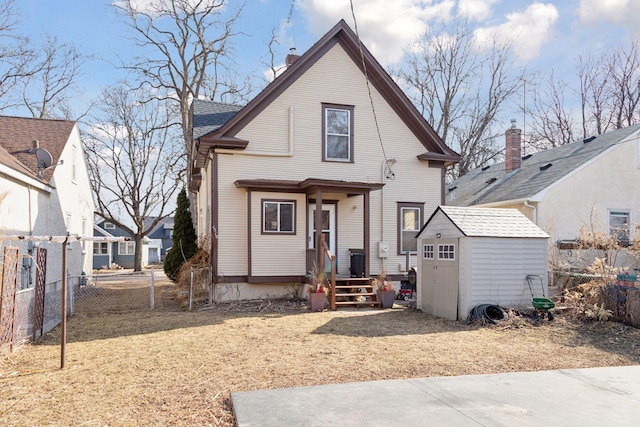 rear view of house featuring fence, an outdoor structure, and a storage shed