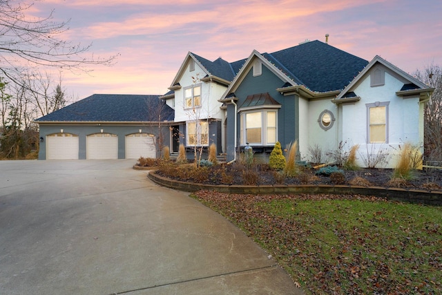 view of front of home with a garage, driveway, a shingled roof, and stucco siding