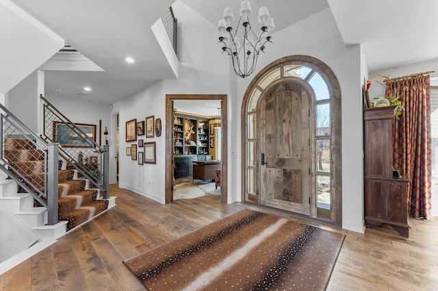 entrance foyer with recessed lighting, wood-type flooring, a chandelier, baseboards, and stairs