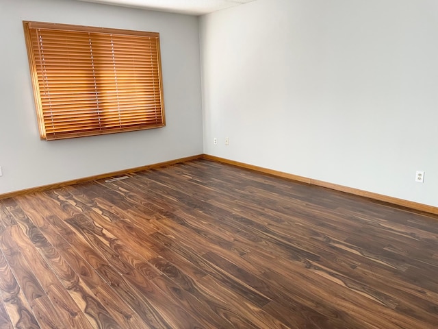 empty room featuring baseboards and wood finished floors