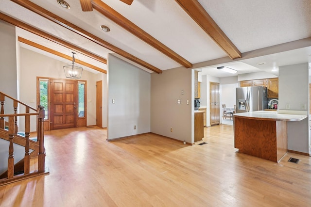 interior space with visible vents, lofted ceiling with beams, stairway, light wood-style floors, and a notable chandelier