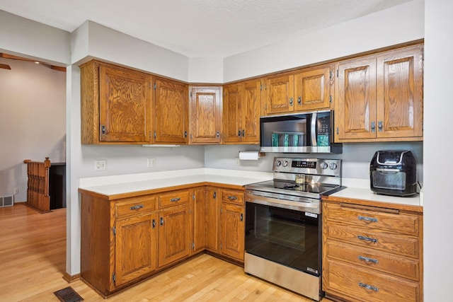 kitchen featuring stainless steel appliances, light countertops, visible vents, and brown cabinets