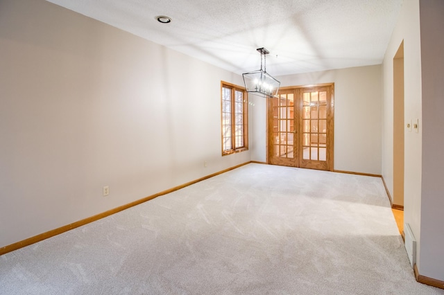 spare room with carpet, baseboards, a textured ceiling, and french doors