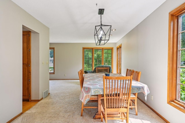 dining area featuring light carpet, baseboards, visible vents, and a chandelier