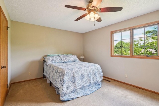 bedroom with a textured ceiling, a ceiling fan, visible vents, baseboards, and carpet