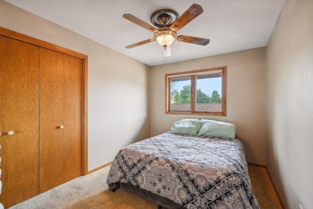 carpeted bedroom featuring a ceiling fan, a closet, baseboards, and a textured ceiling