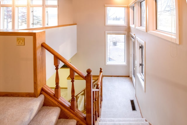 staircase with carpet floors, visible vents, and baseboards