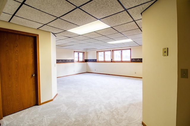 below grade area featuring carpet floors, a drop ceiling, and baseboards