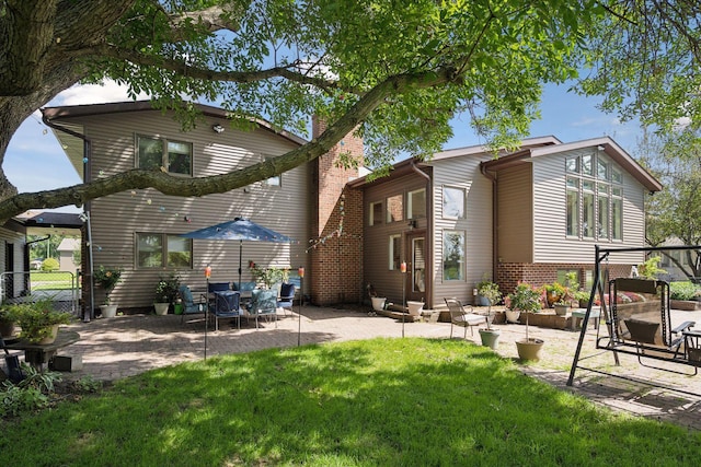 rear view of house featuring fence, a yard, a gate, a chimney, and a patio area